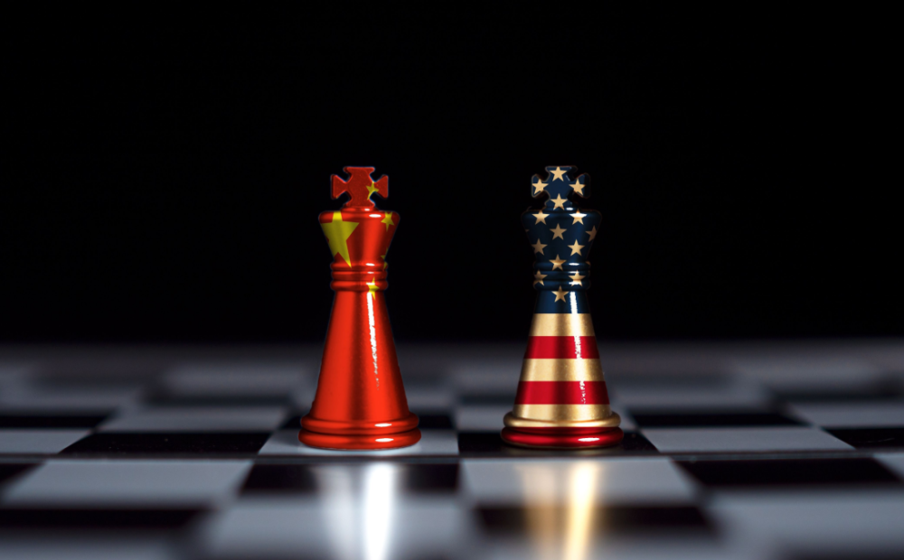 Chess pieces stand text to each other wrapped in the US and Chinese flags