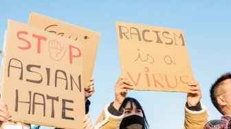 Signs of protestors, "Stop Asian Hate" and "Racism is a Virus"