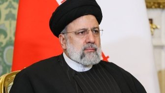 A picture of President Ebrahim Raisi seated in front of an Iranian flag.